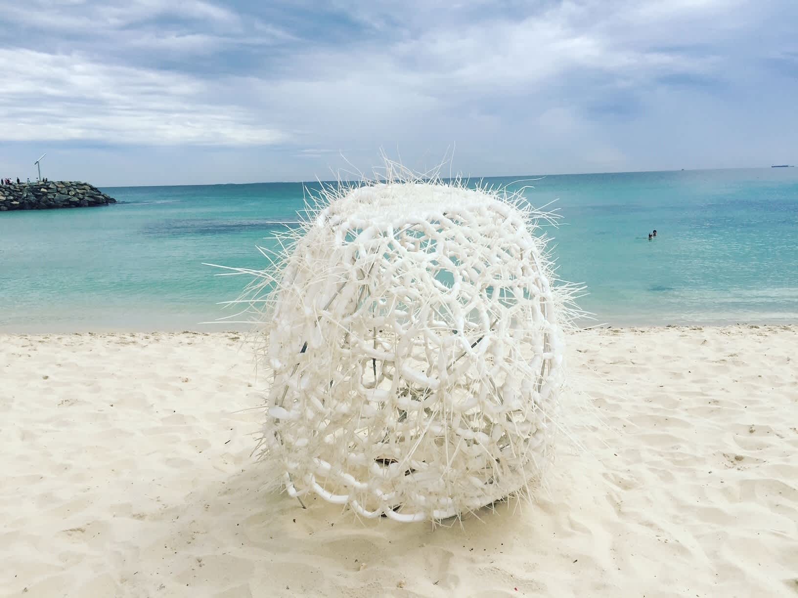 White sculpture on sand in front of turquoise water of Cottesloe Beach