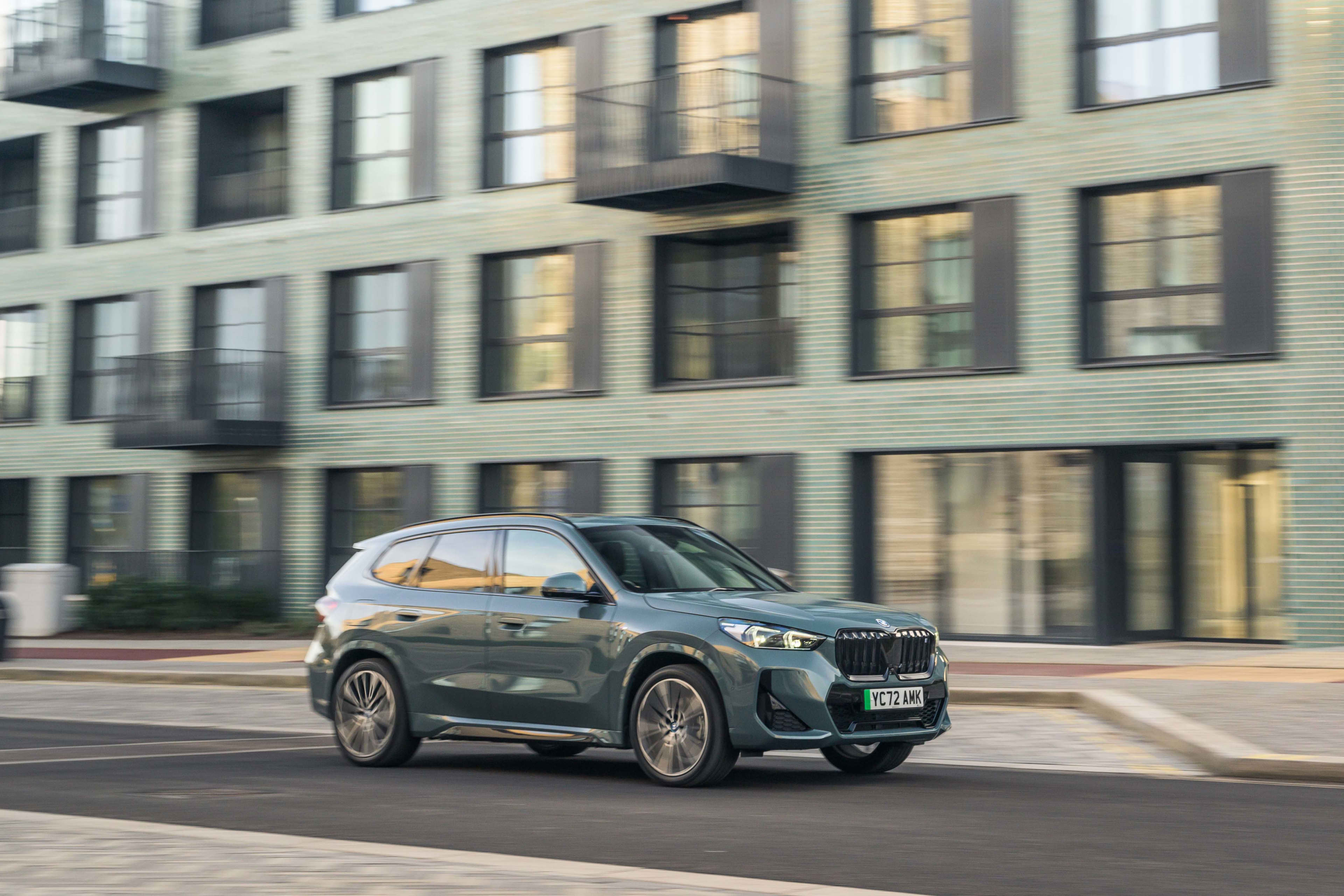 A grey BMW iX in front of an old city building