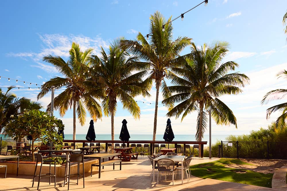 Palm trees line a beachfront al fresco area