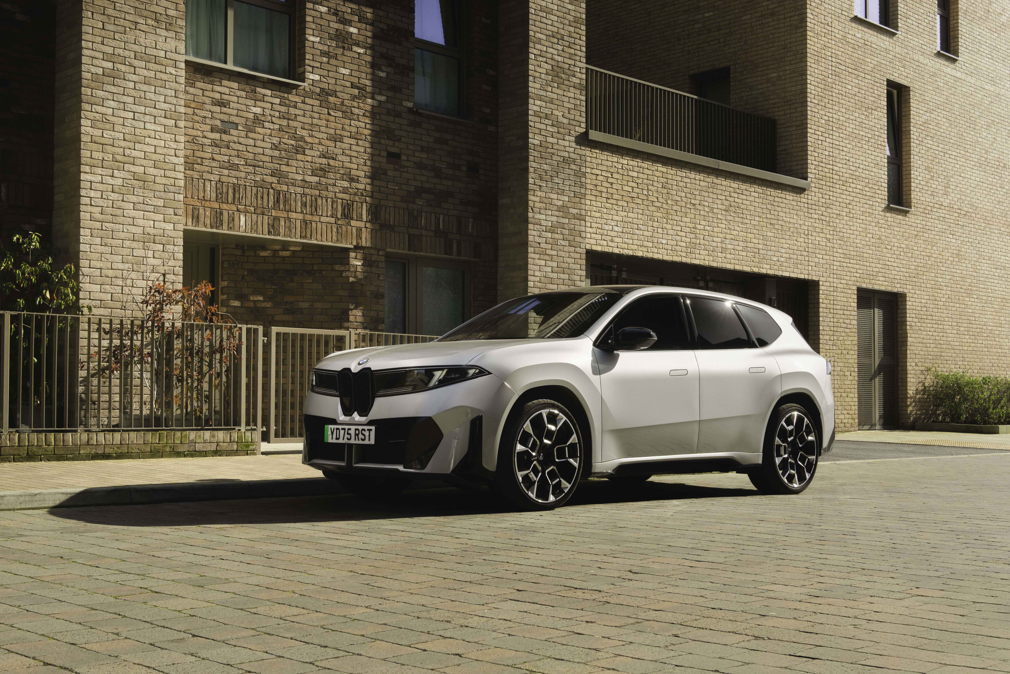 A white BMW ix3 50 xdrive parked in front of a residential building