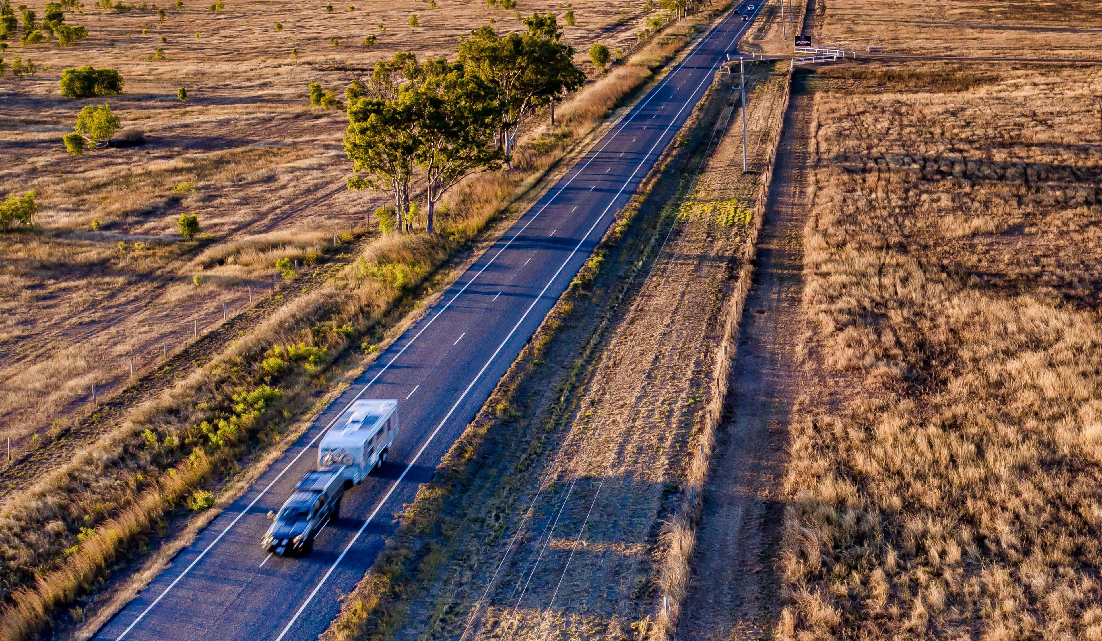 Aerial image of a car towing a caravan on a country highway