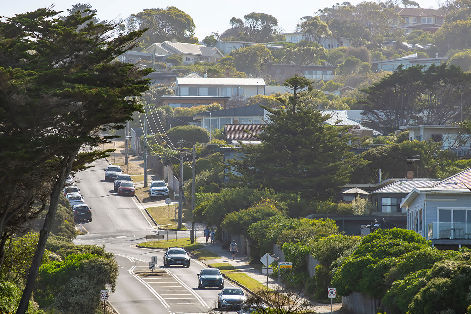 A suburban street with cars parked and some in motion