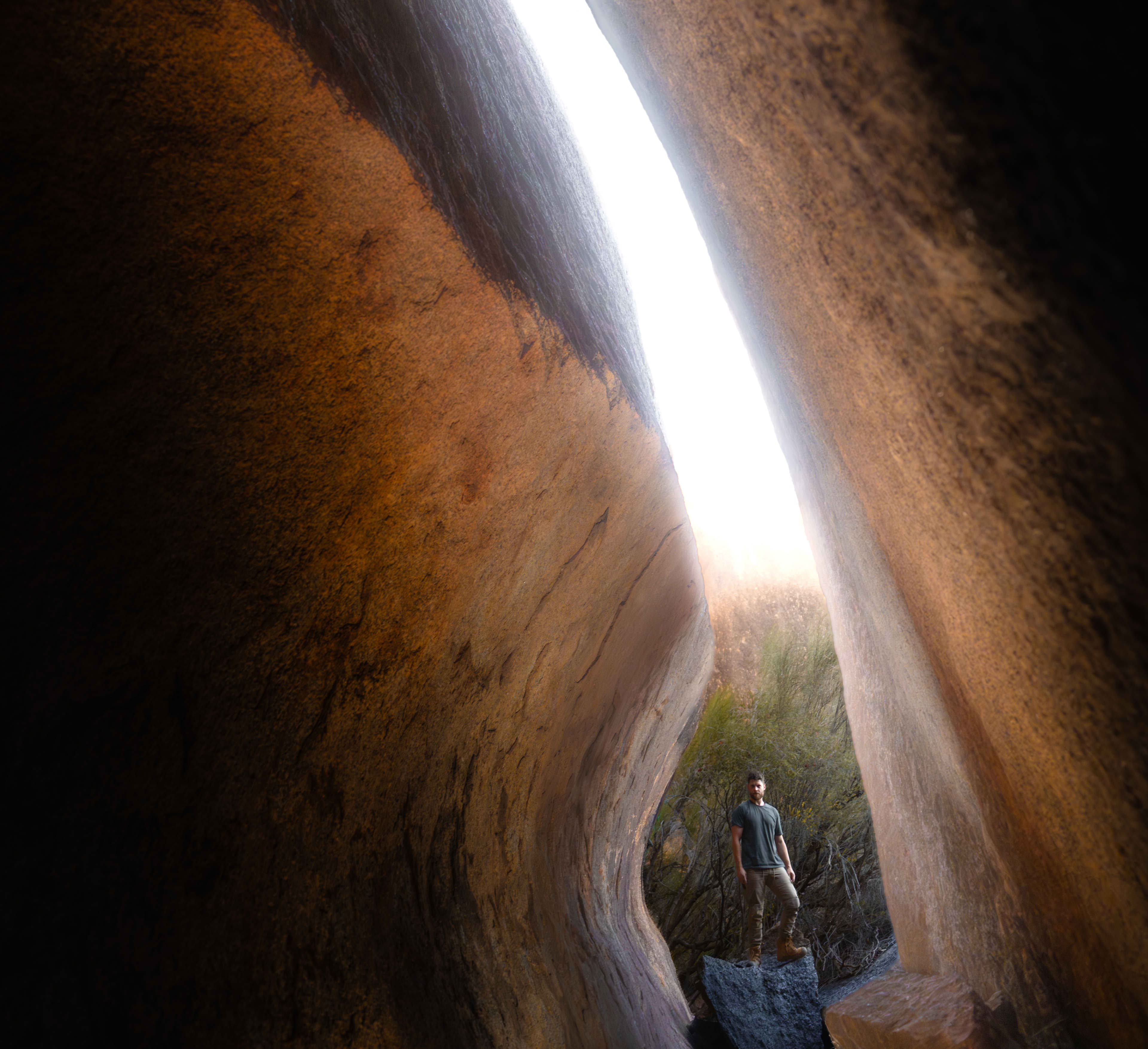 A man stands at the base of a deep rock crevice