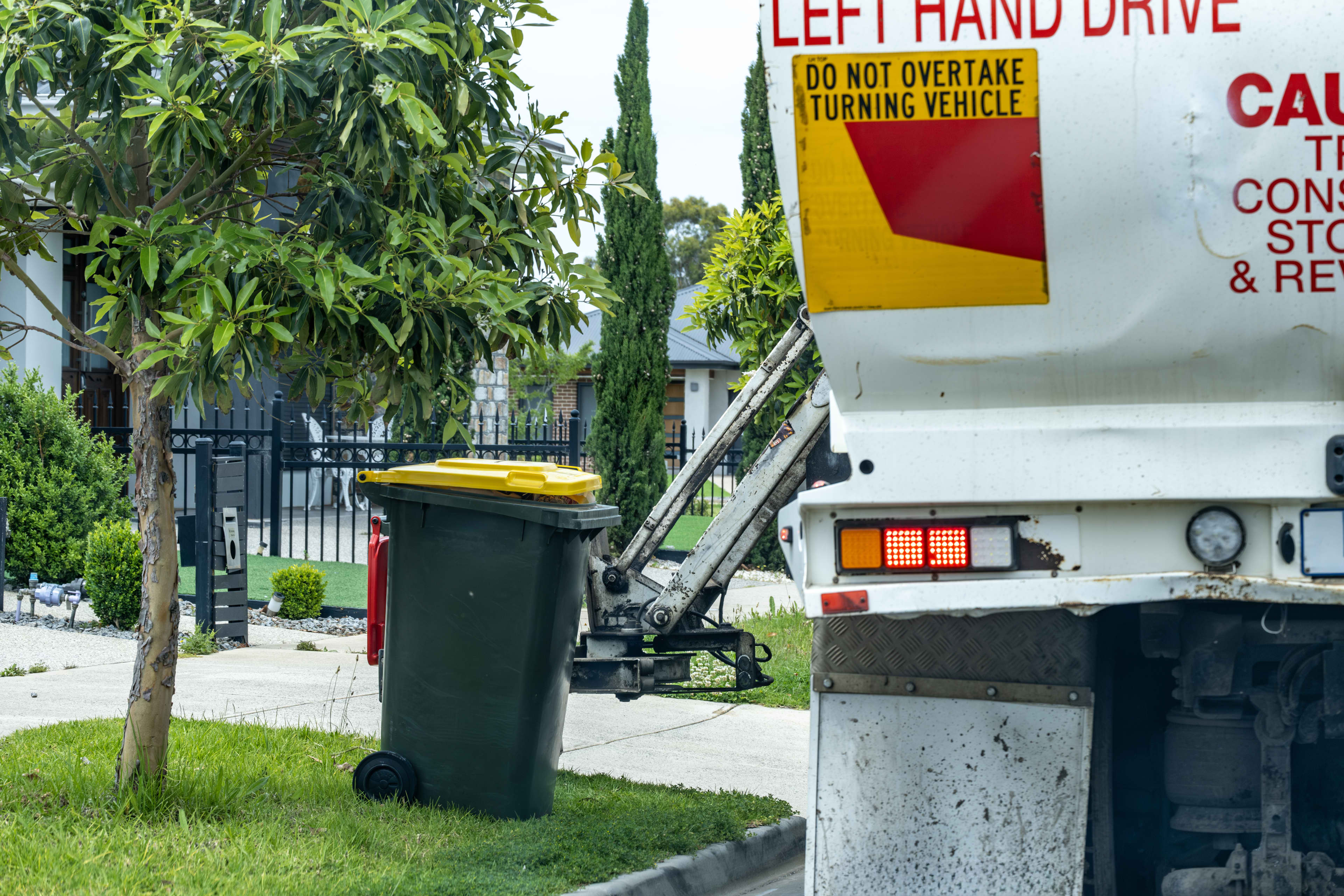 The rear of a rubbish collection truck showing a Do No Overtake Turning Vehicle sign