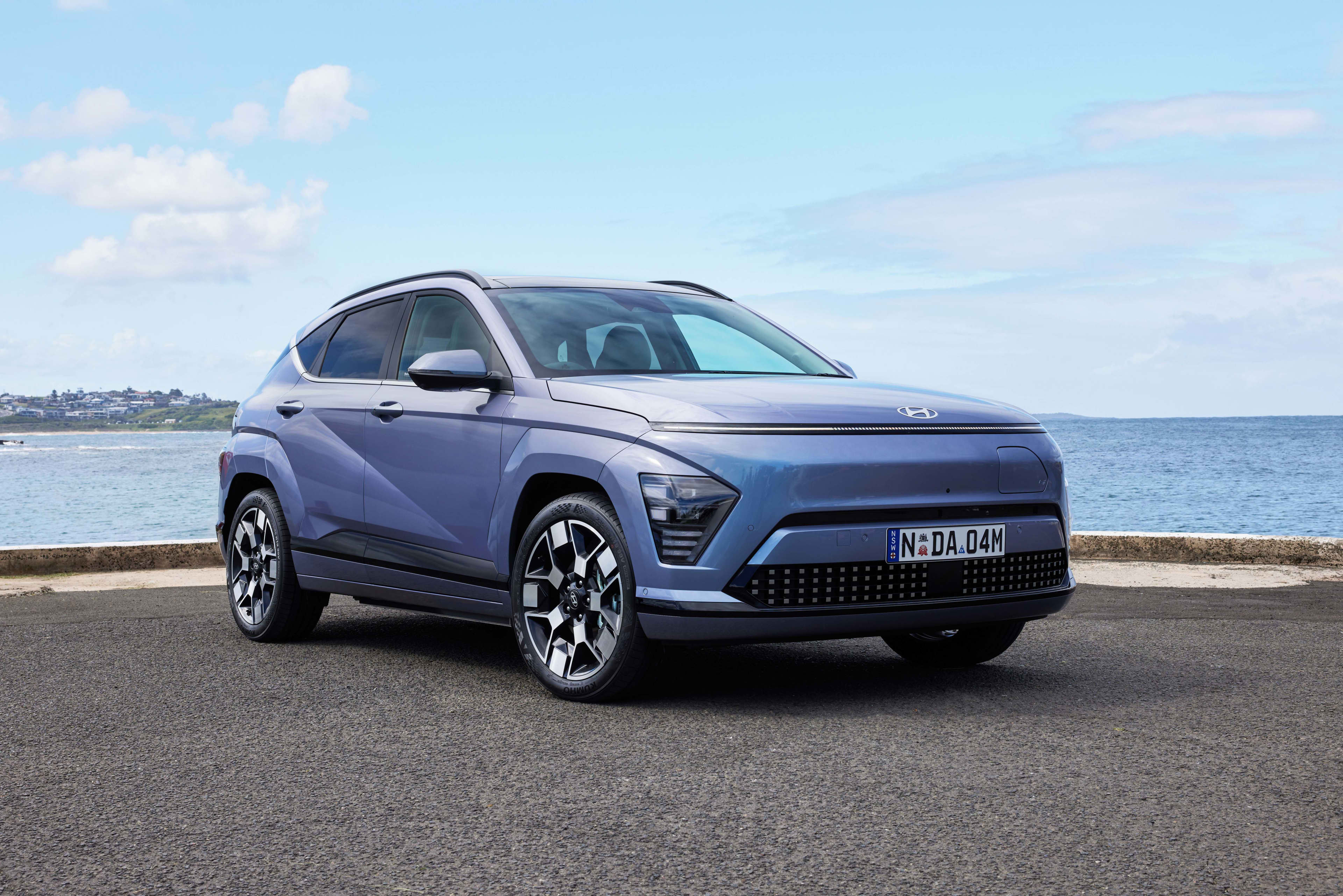 A blue EV Hyundai Kona electric premium parked near a beach