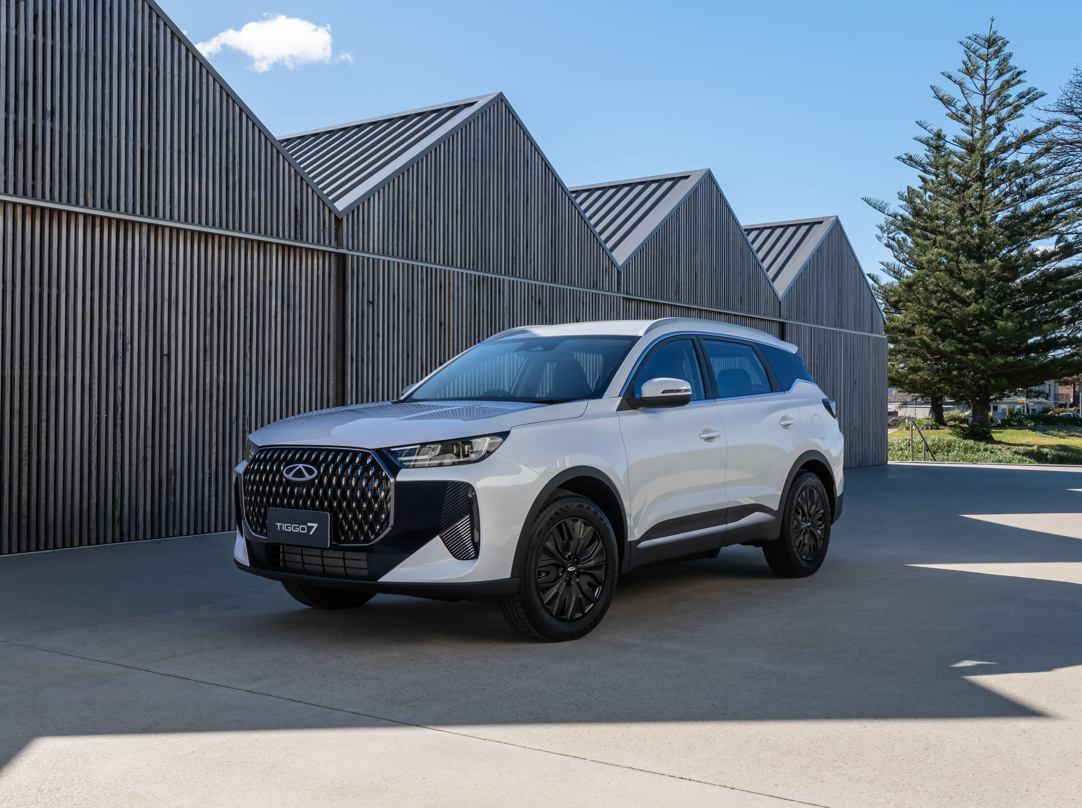 A white Chery Tiggo 7 PHEV SUV near sheds