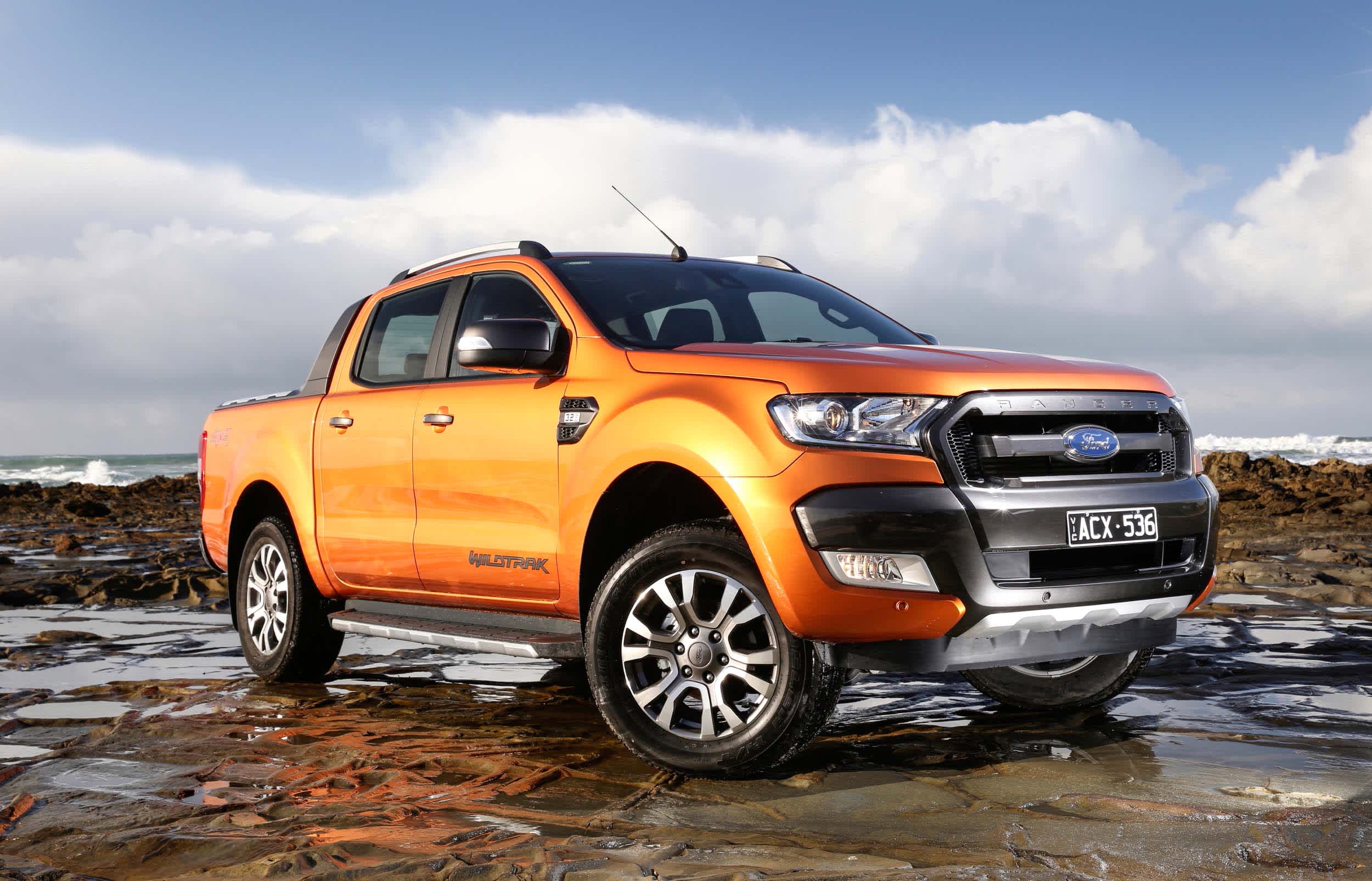 A burnt orange Ford Ranger on a rocky beach