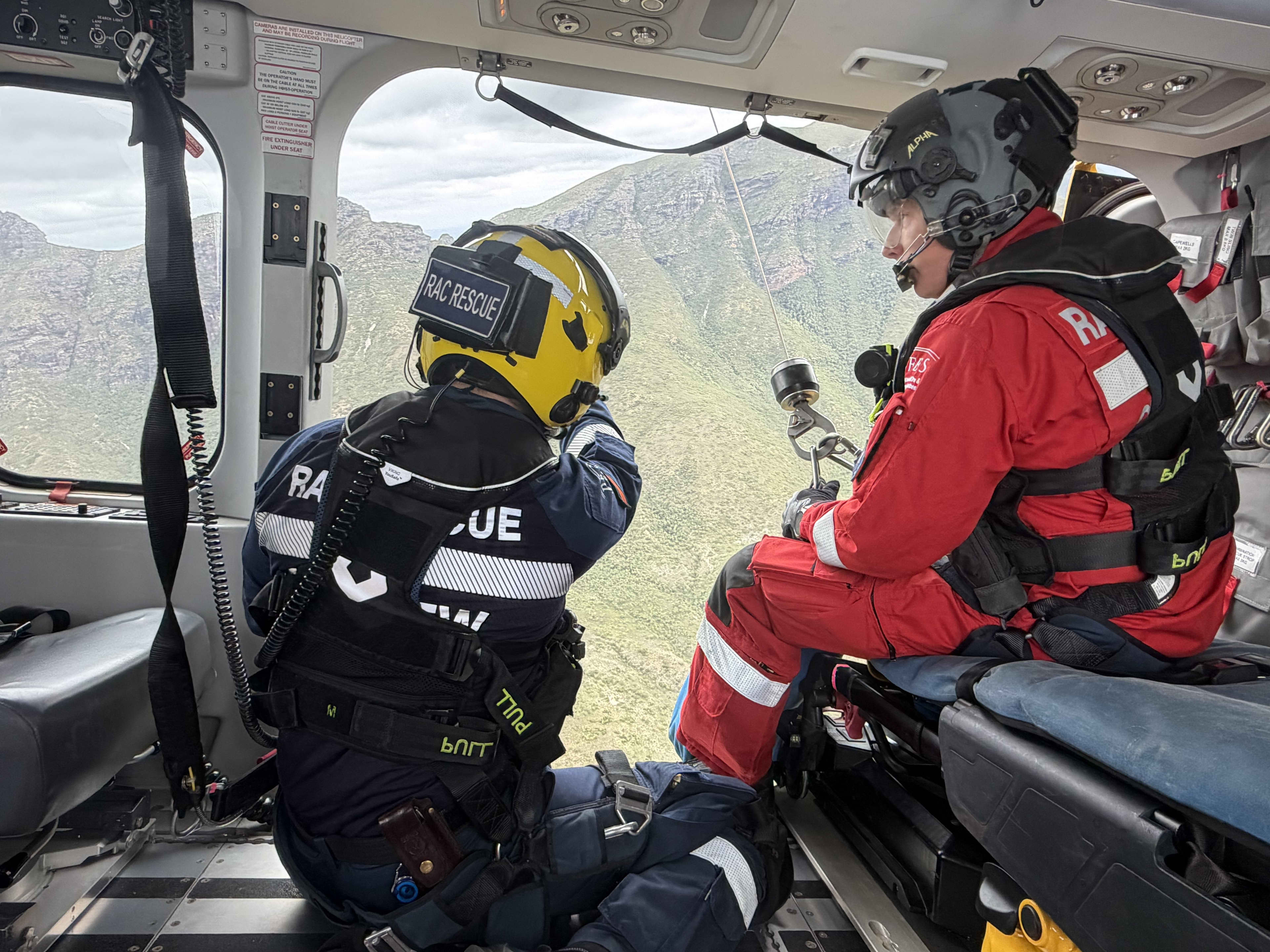 Inside the RAC rescue helicopter. Two safety personal wait at the open door to complete a rescue.