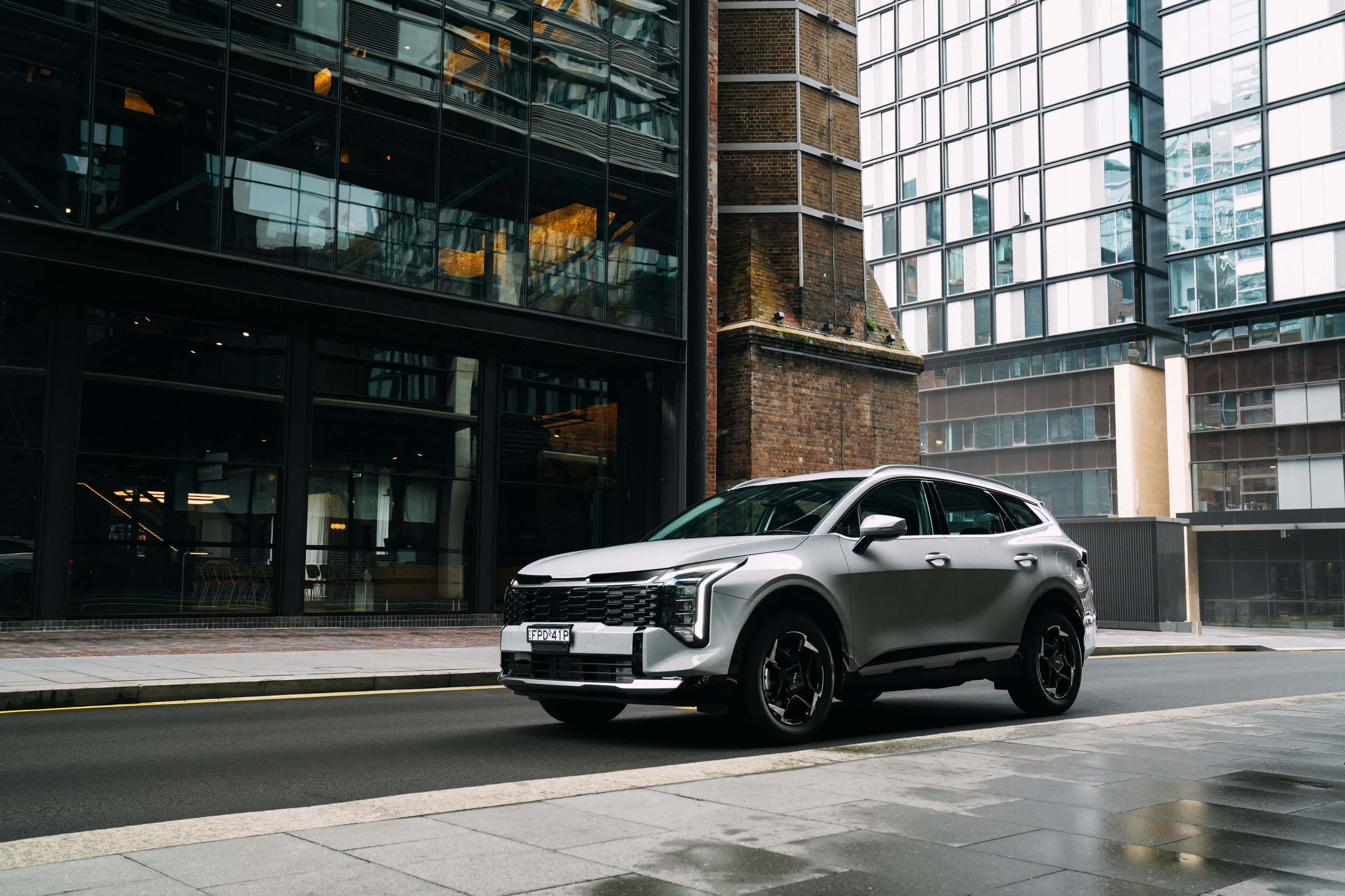 A silver KIA SPORTAGE parked on  a city street