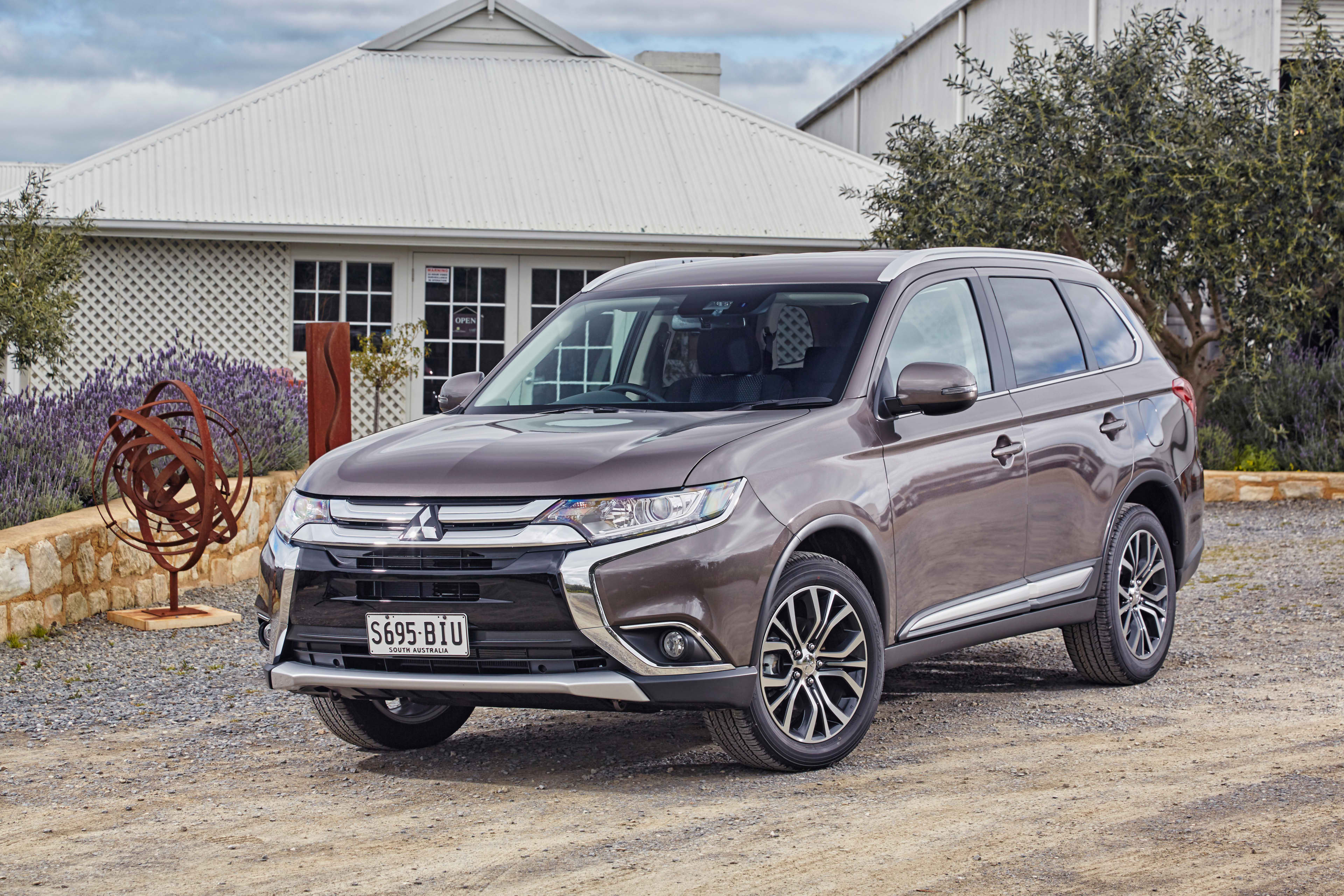 A grey Mitsubishi Outlander parked in front of a house.