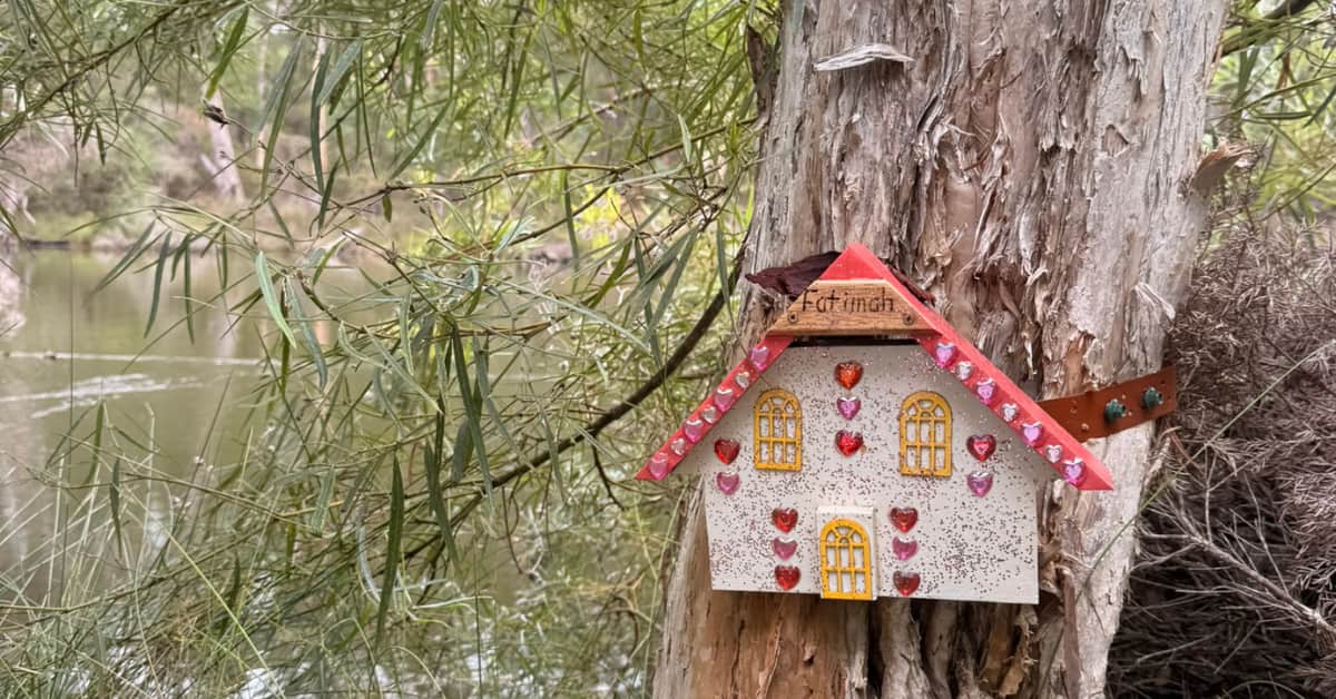 Tiny decorated fairy door on outside of tree by river
