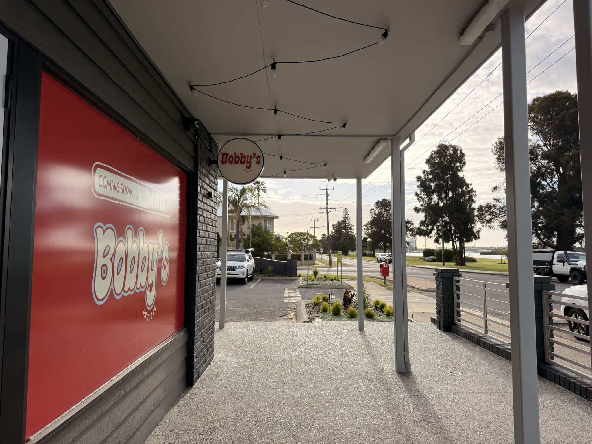Waterfront cafe under development with Bobbys signage and red window poster.