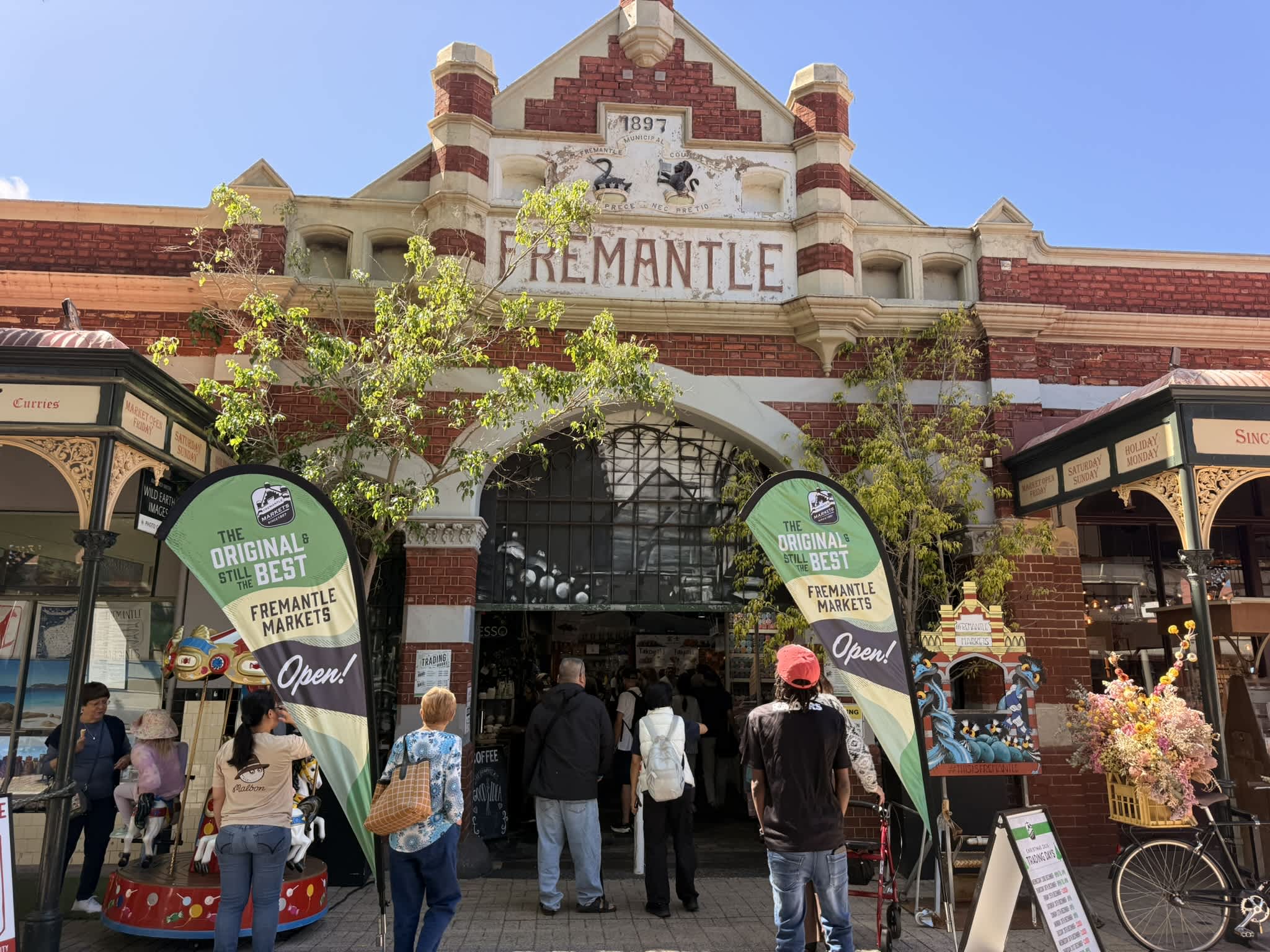 Heritage building with wording Fremantle on it and lots of signs and shopfronts with people milling about outside.