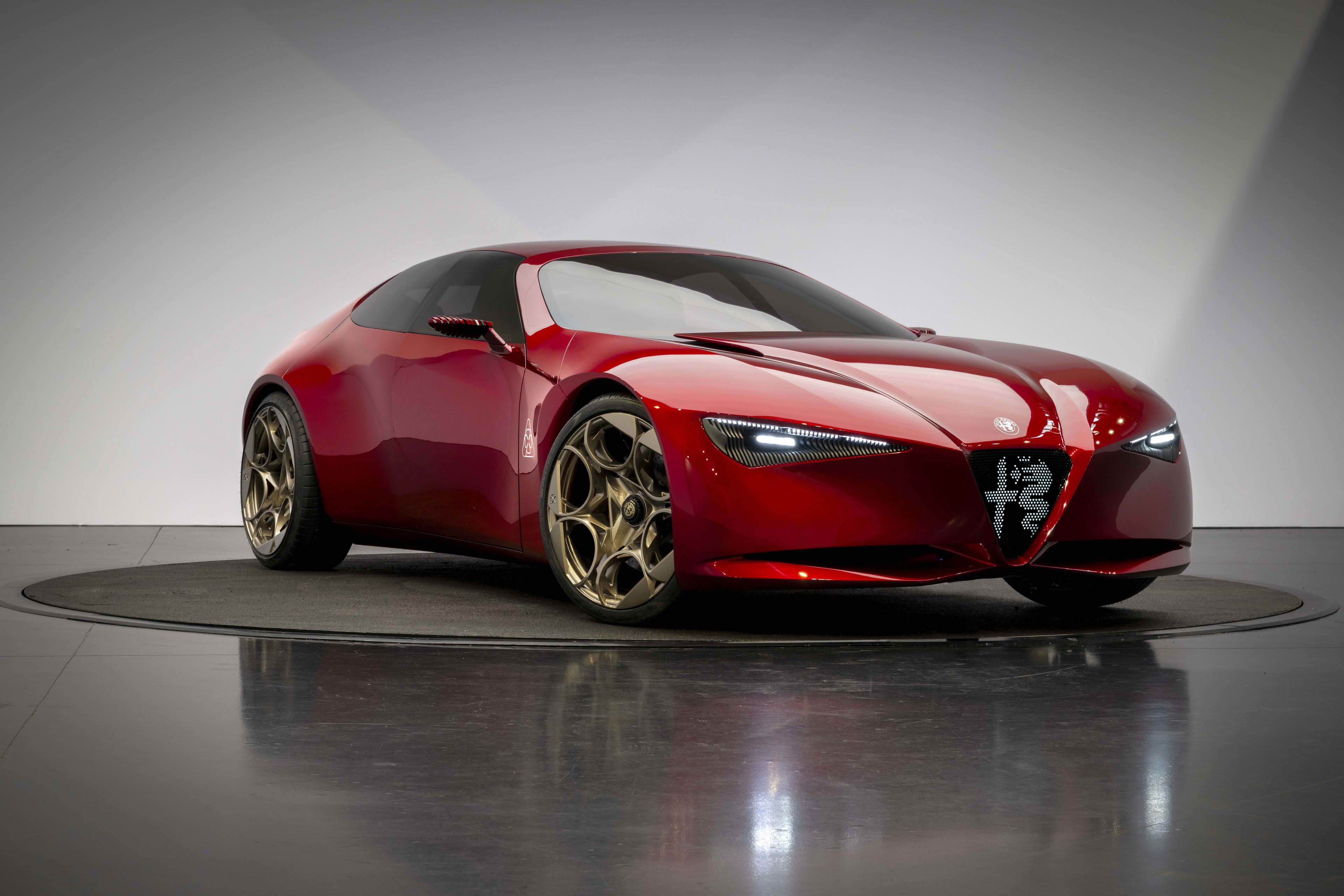 A shiny red sports car on a circular turntable under studio lighting.