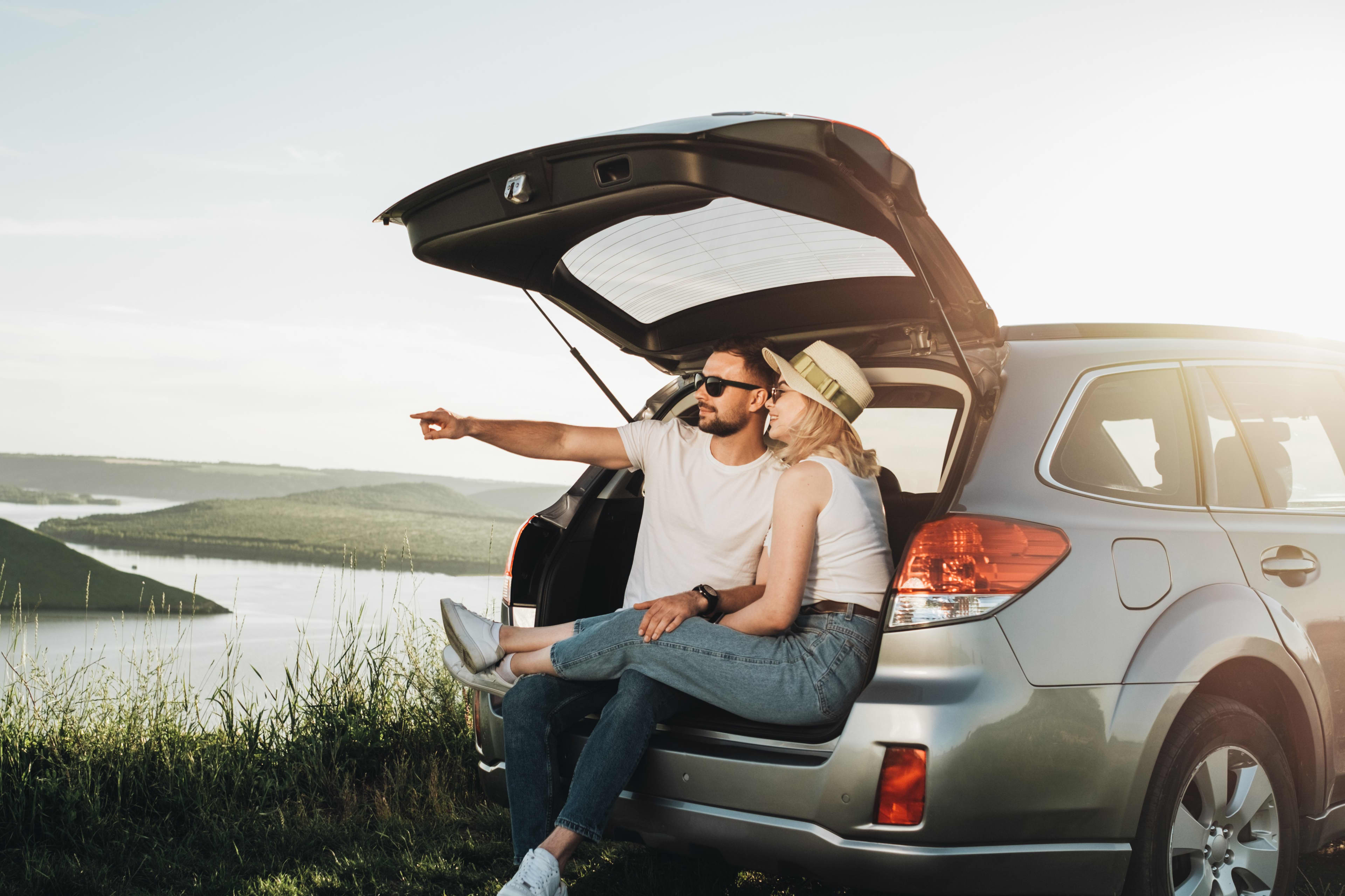Couple sitting in the boot of their car looking at a nice view
