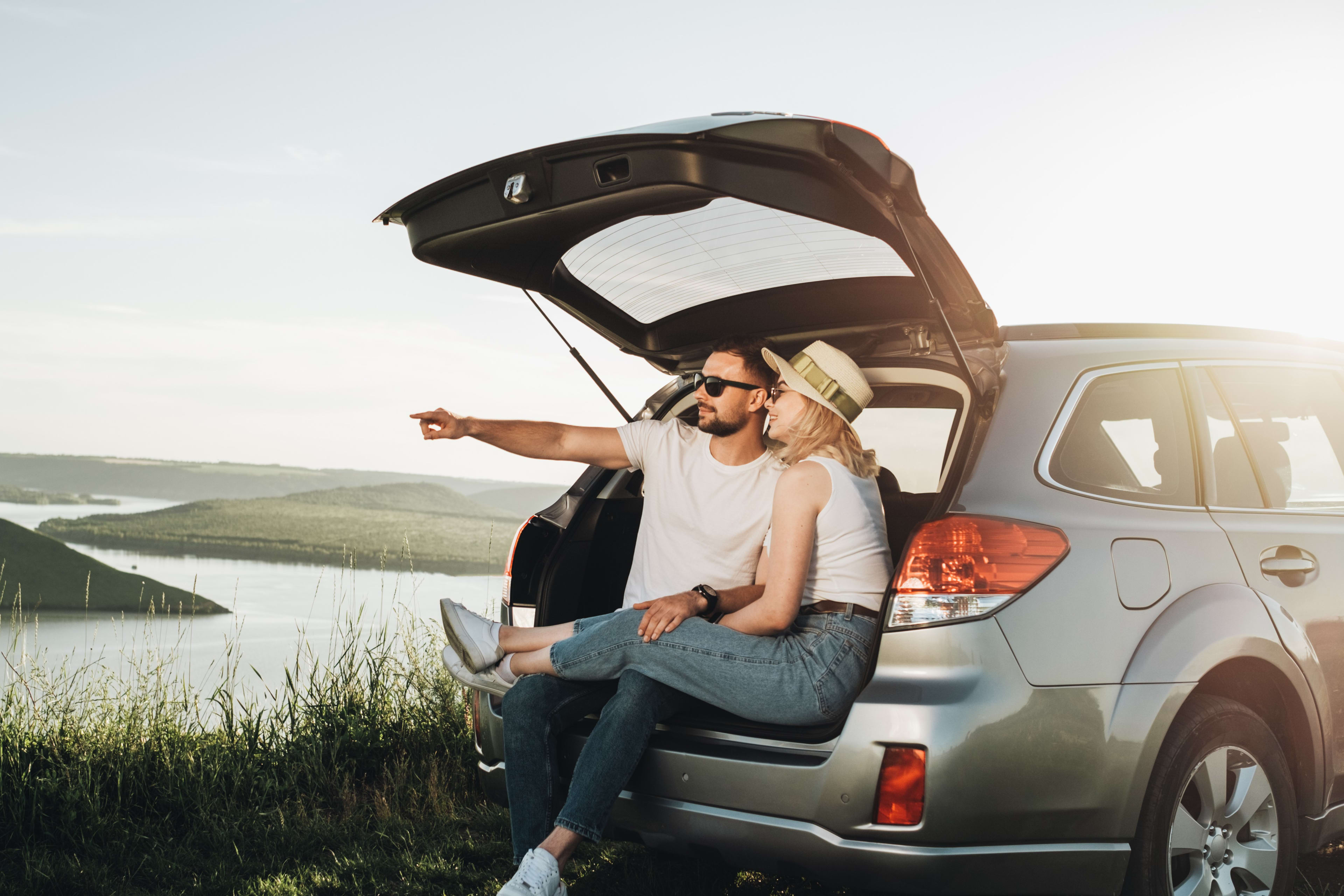 Couple sitting in the boot of their car looking at a nice view